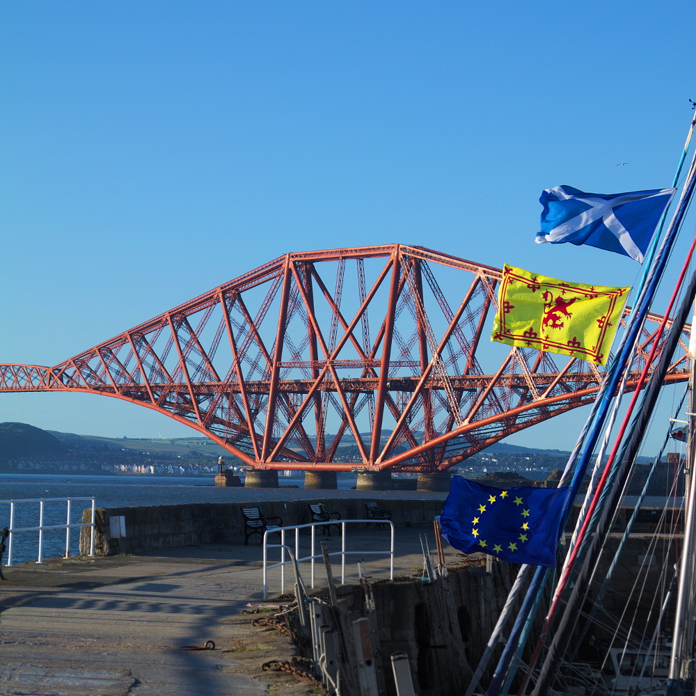 Forth Rail Bridge with Scotland and EU flags on a ship sail in front in harbour